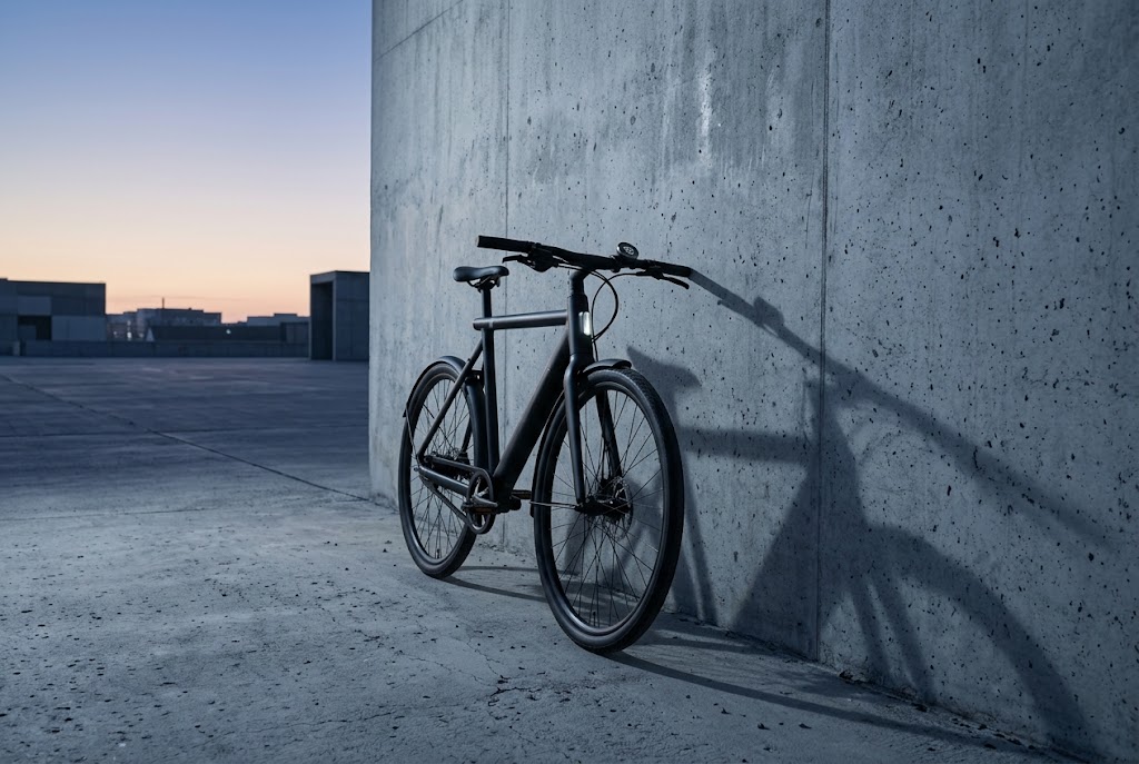 A black e-bike against a concrete wall at dawn